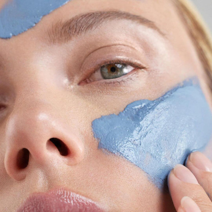 Woman indulging in self-care: applying our Resurfacing Face Mask for a rejuvenating skincare experience.