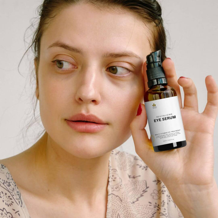 Woman holding a bottle of our revitalizing eye serum, a natural skincare essential for puffiness, dark circles and revitalized skin